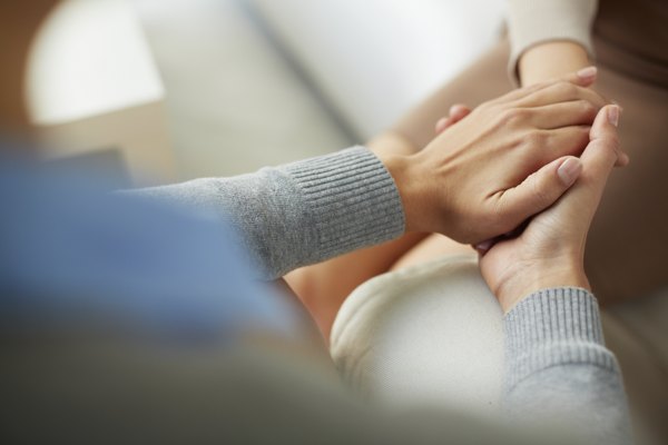 Friend holding hands of caregiver in support