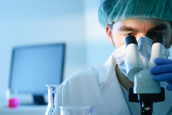 Male doctor looking through microscope for lab test