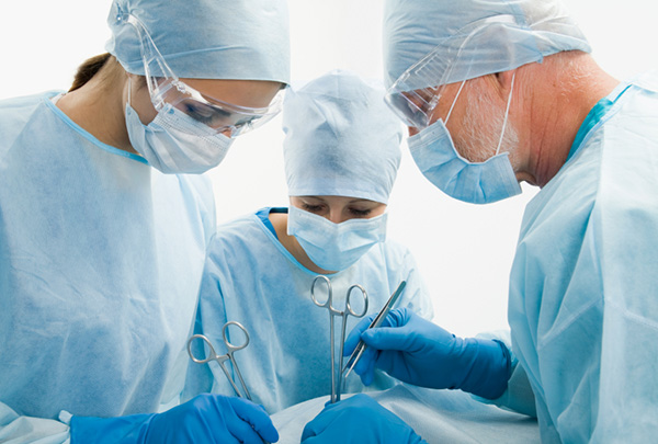 Three doctors in scrubs operating on a patient